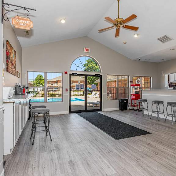 a spacious room with a bar area and a view of a pool through an arched window.