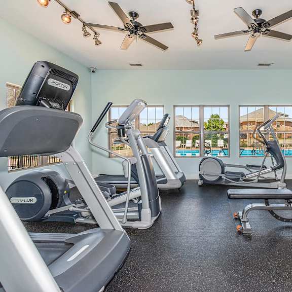 a well-equipped home gym with treadmills, elliptical machines, and dumbbells.