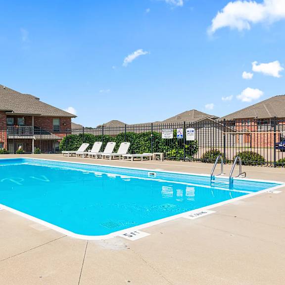a large swimming pool in front of a building with a fence around it.