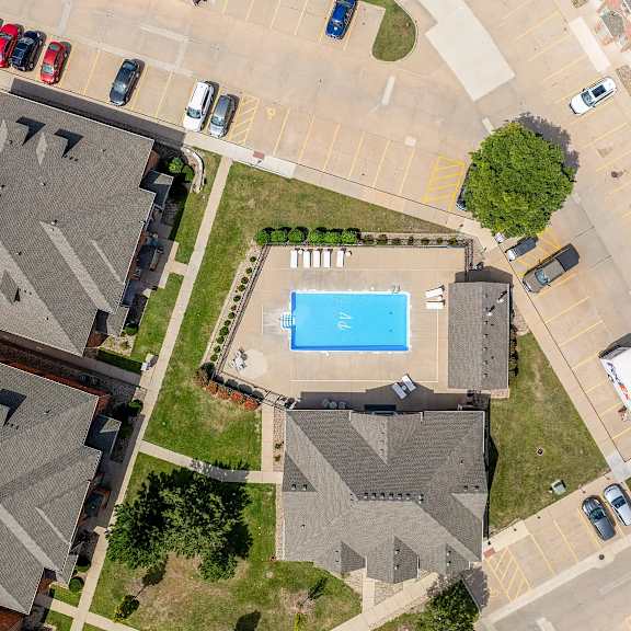 a swimming pool is surrounded by houses and cars.