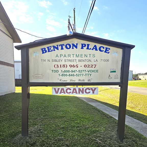 a sign for benton place apartments with a vacancy sign.