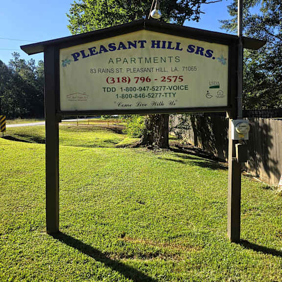 a sign for pleasant hill apartments is displayed in a grassy area.