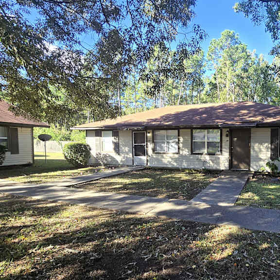 a house with a brown roof and a tree in front.