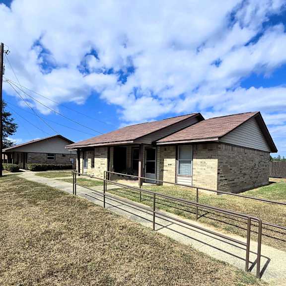 a house with a brown roof and a fence in front of it.