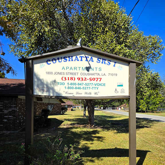 a sign for coushatta street apartments stands in front of a house.