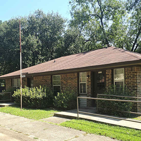 a brick house with a brown roof and a flag on a pole.
