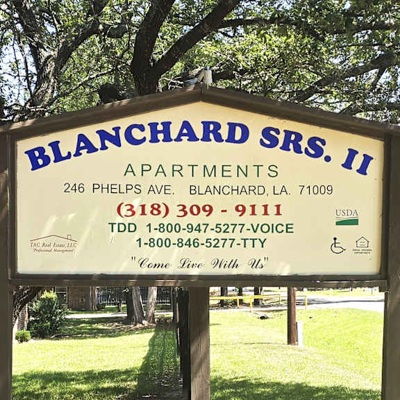 a sign for blanchard sr.s. ii apartments is displayed in front of a tree.