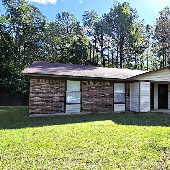 a house with a brown roof and white trim is surrounded by trees.