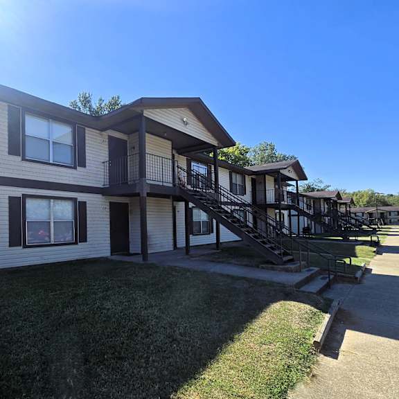a house with a balcony and a deck is surrounded by a grassy area.