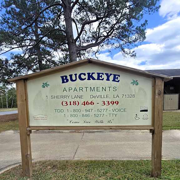 a sign for buckeye apartments is displayed in front of a tree.