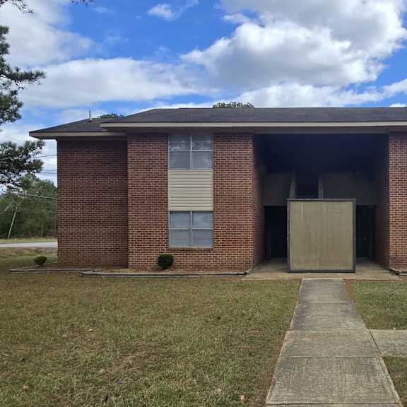 a brick building with a concrete walkway in front.