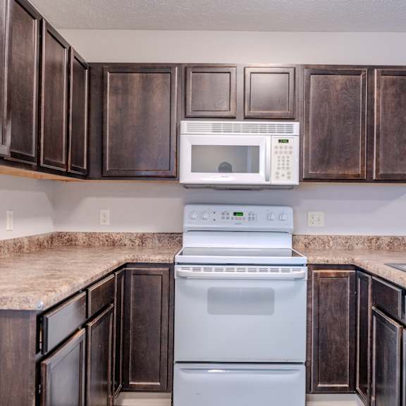 a kitchen with brown cabinets and a white microwave.