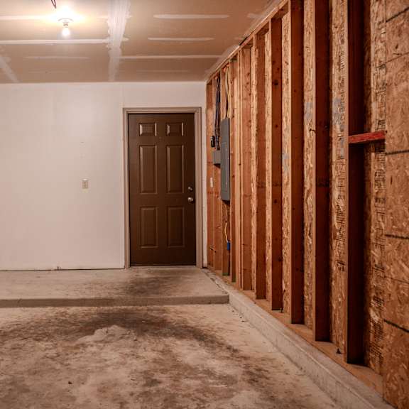 a room under construction with a brown door and wooden framing on the wall.