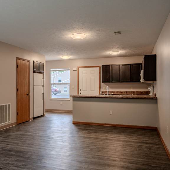 a large empty room with wooden floors and a window.