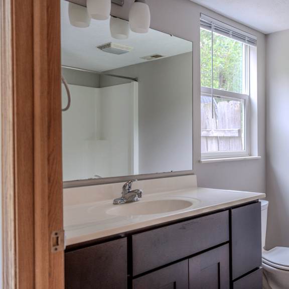 a bathroom with a toilet, sink, and mirror.