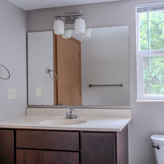 a bathroom with a toilet, sink, and mirror.