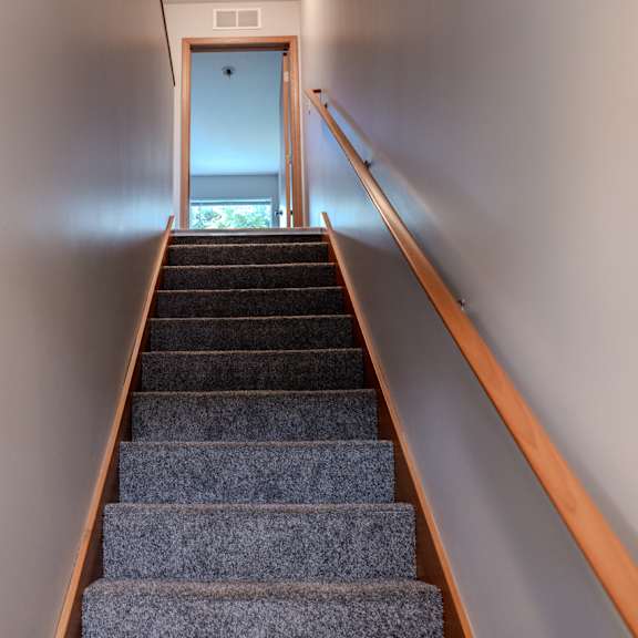 a staircase with a wooden handrail leading to a door.