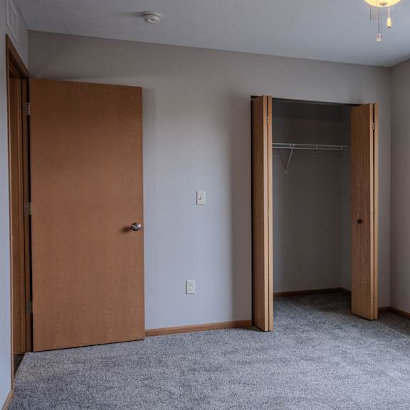 a room with a brown door and a grey carpet.