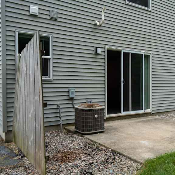 a house with a grey siding and a window with a curtain.