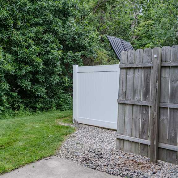a white refrigerator is placed next to a wooden fence.
