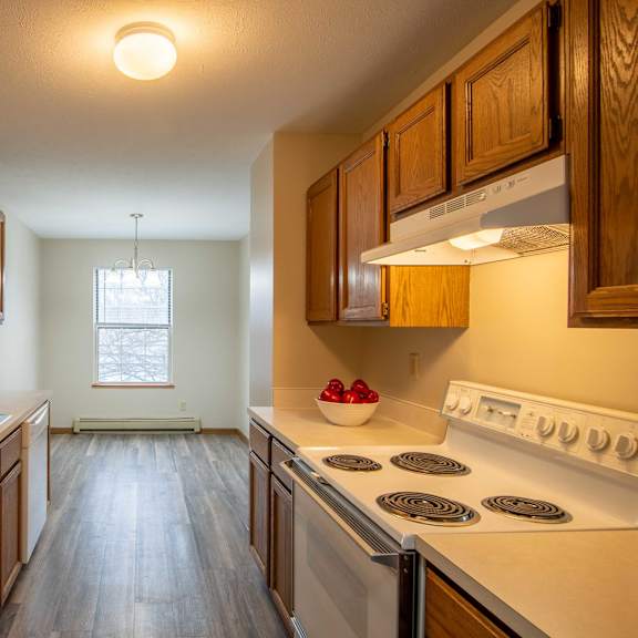 A kitchen with a stove, sink, and cabinets.