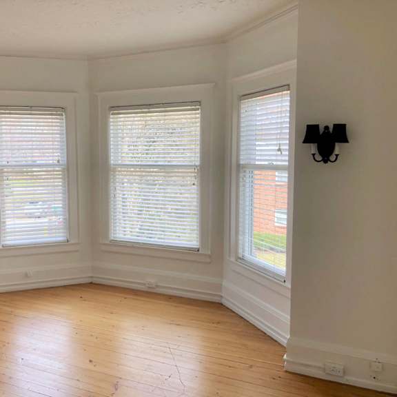 a room with wooden floors and three windows.