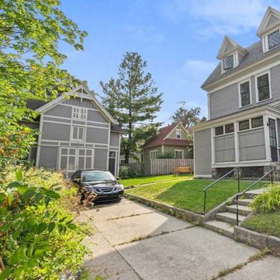 a large grey house with a car parked in front.
