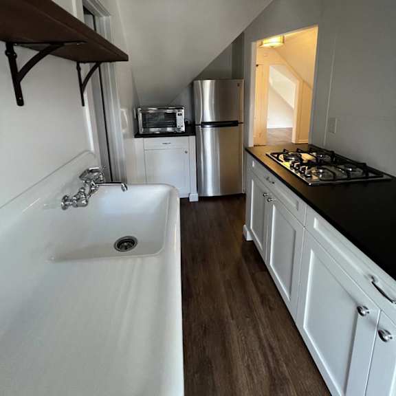 a white sink with a silver faucet is on the left side of a kitchen.