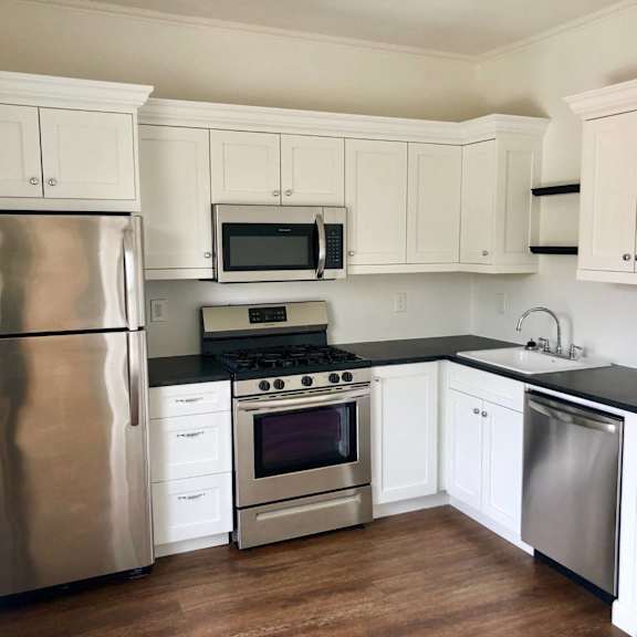 a kitchen with white cabinets and black countertops.