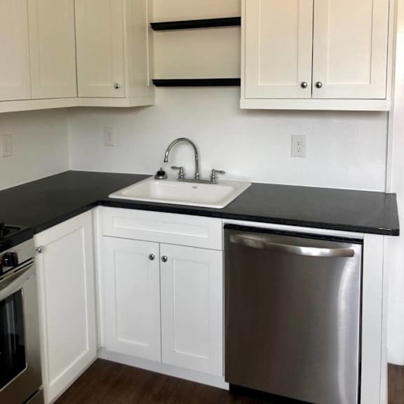 a kitchen with white cabinets and a black countertop.