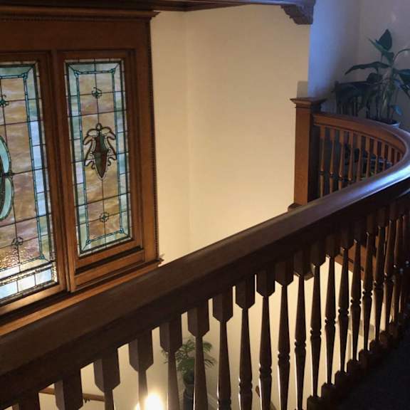 a staircase with a wooden banister and a stained glass window.