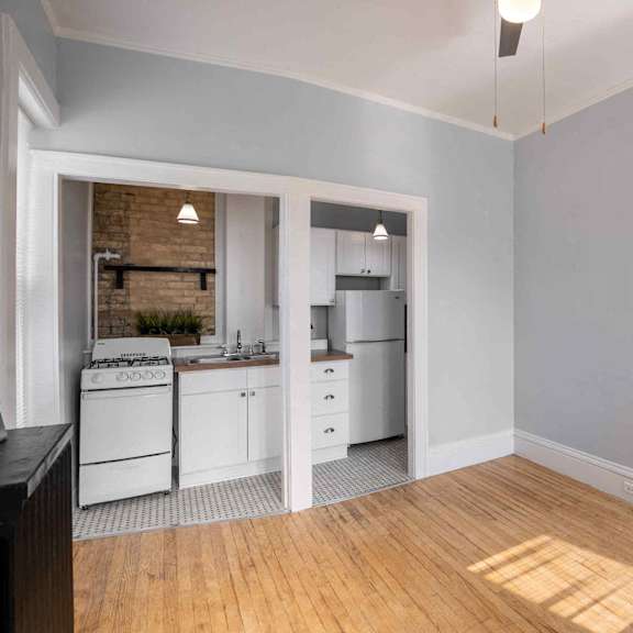 a kitchen with white appliances and wooden floors.