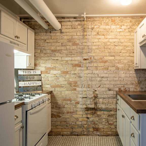 a kitchen with a brick wall and white appliances.
