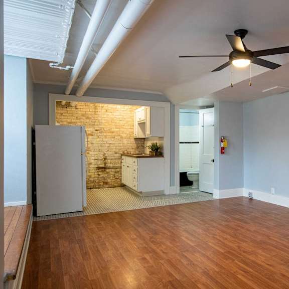 a room with a ceiling fan and wooden floors.