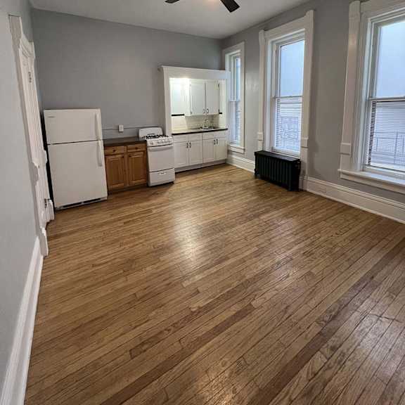 a kitchen with a white refrigerator, white cabinets, and a black fan.