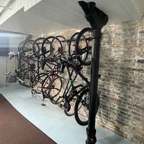 a bike rack with many bicycles parked against a brick wall.