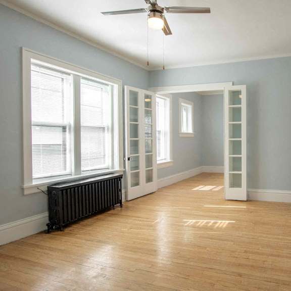 a room with a ceiling fan and wooden flooring.