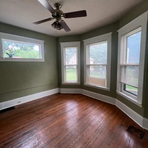 a ceiling fan is mounted on a wall in a room with wood flooring and skylight windows.