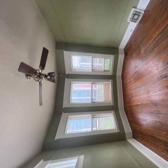 a room with a ceiling fan and two windows.