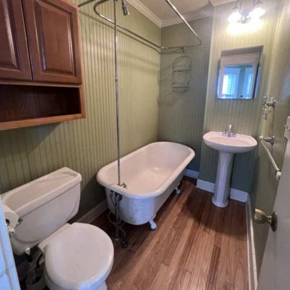 a bathroom with a toilet, sink, and shower.