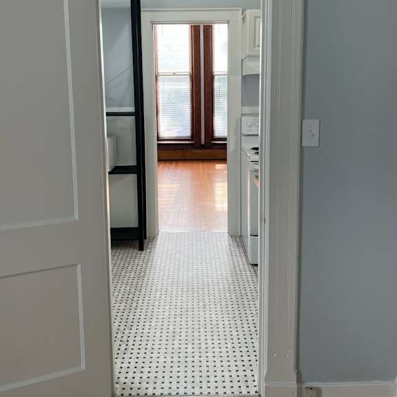 a hallway with a white door and a black door on the other side.