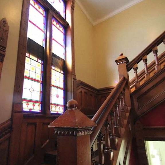 a staircase with a wooden handrail and a stained glass window.