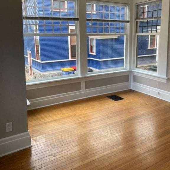a room with wooden floors and large windows overlooking a building.