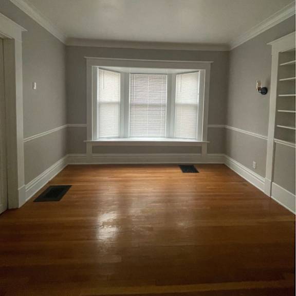 a room with wooden floors and a window with blinds.