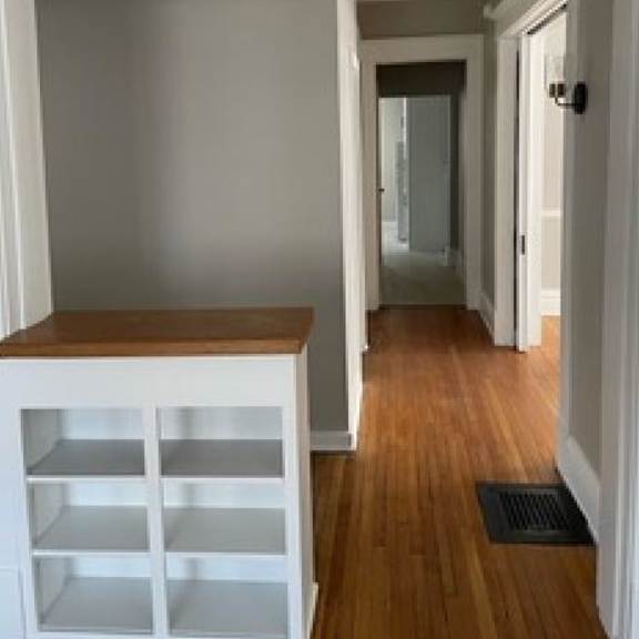 a hallway with a white cabinet and a black doormat.