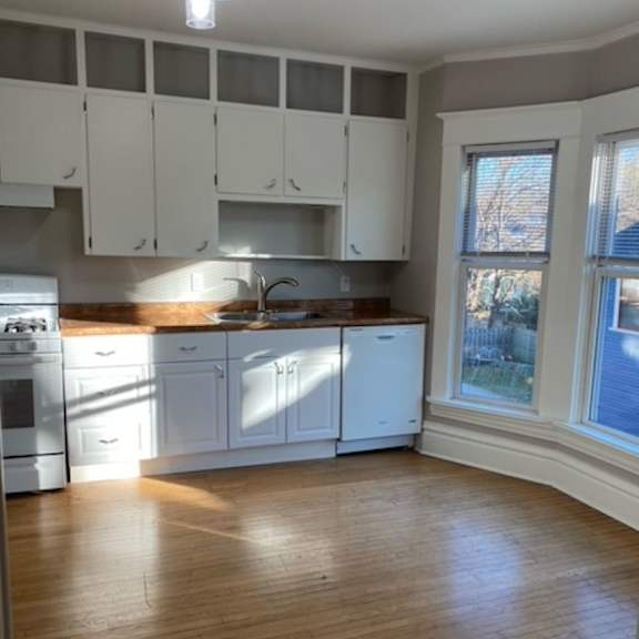 a kitchen with white cabinets and a wooden floor.