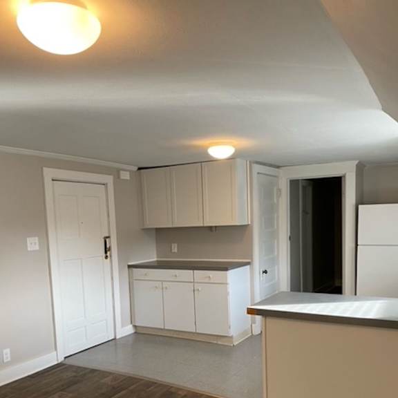 a kitchen with white cabinets and a wooden floor.