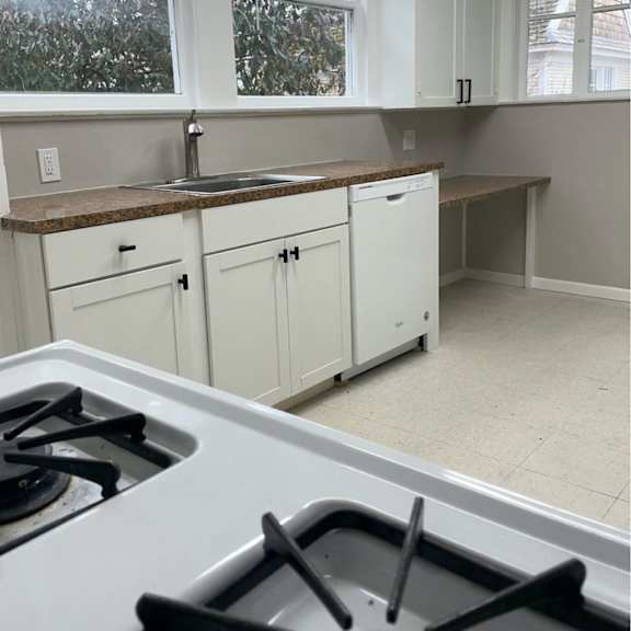 a kitchen with white cabinets and a stove top oven.