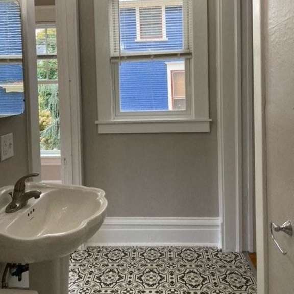 a bathroom with a white sink and a window with blinds.