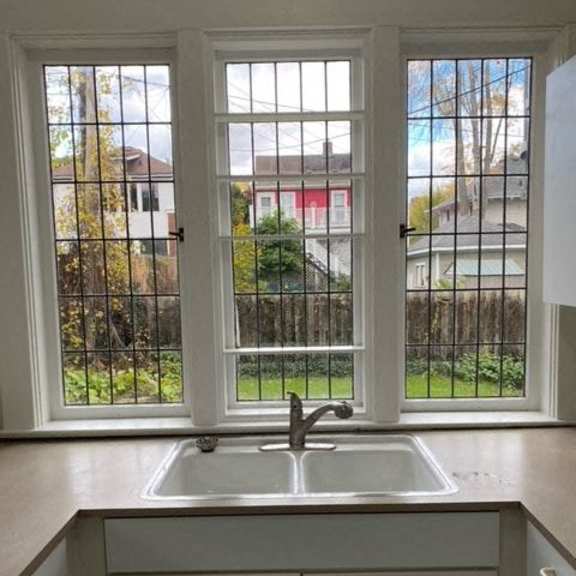 a kitchen with a sink and a window overlooking a fence.